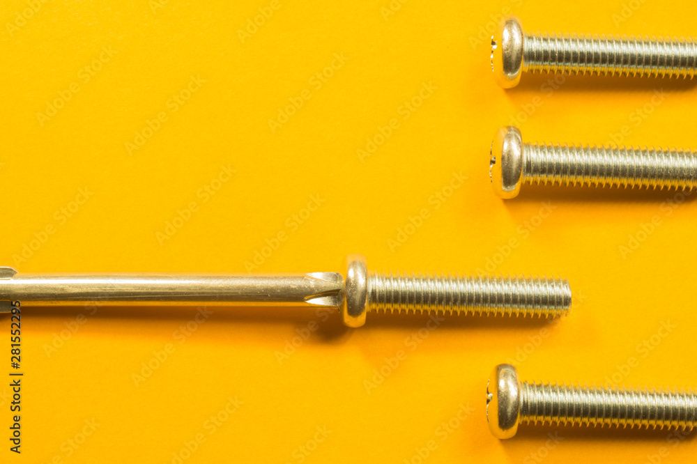 Screws and screwdriver on a yellow background Screws and screwdriver on a yellow background