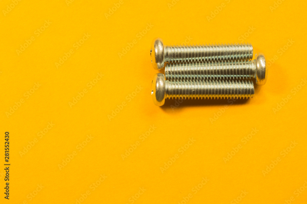 Screws on a yellow background. pile of fasteners Screws on a yellow background. pile of fasteners