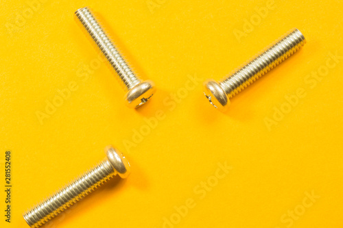 Screws on a yellow background. pile of fasteners