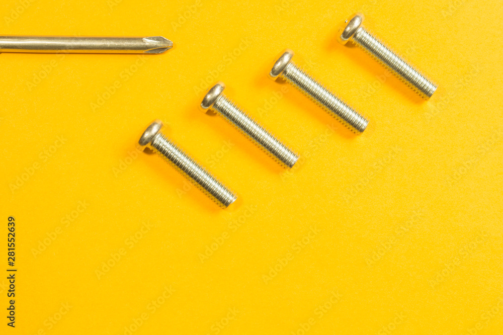 Screws and screwdriver on a yellow background Screws and screwdriver on a yellow background