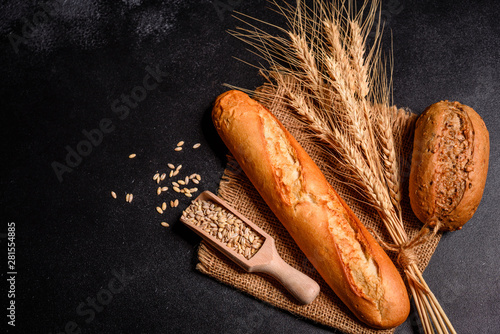 Vers geurig brood met granen en kegels van tarwe tegen een donkere achtergrond. Assortiment van gebakken brood op houten tafel achtergrond