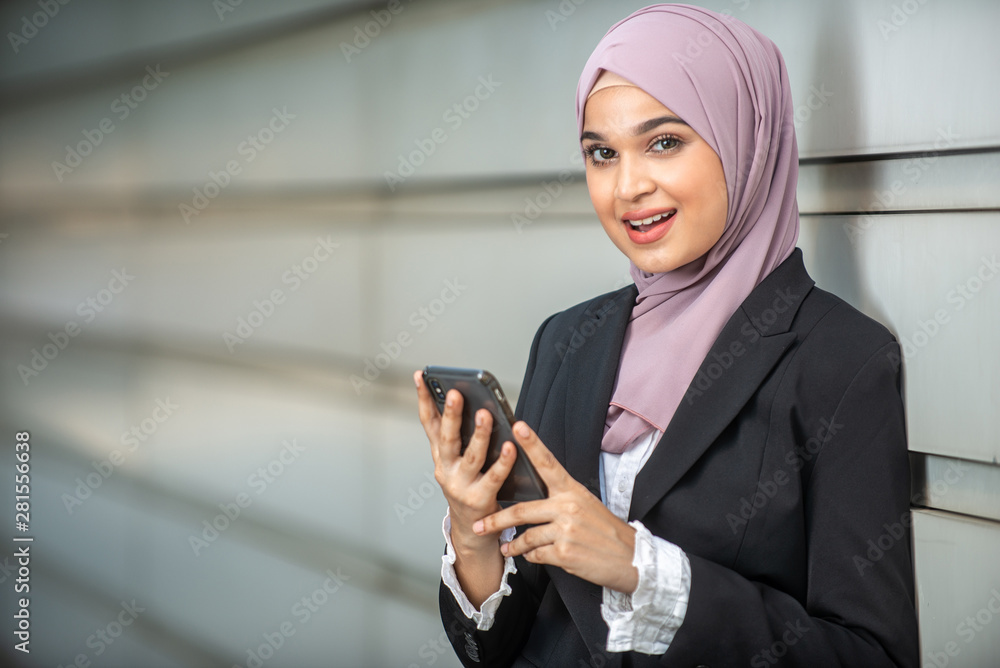 Young Female Muslim Entrepreneur looking at her smartphone. Shallow depth of field. Young Female Muslim Entrepreneur looking at her smartphone. Shallow depth of field.