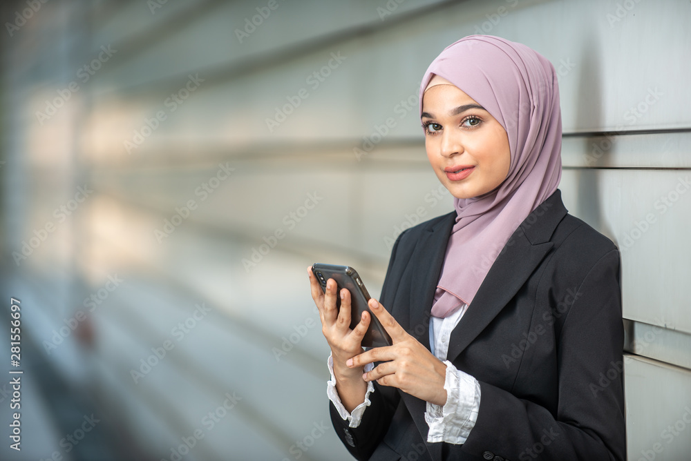 Young Female Muslim Entrepreneur looking at her smartphone. Shallow depth of field. Young Female Muslim Entrepreneur looking at her smartphone. Shallow depth of field.