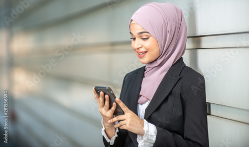 Young Female Muslim Entrepreneur looking at her smartphone. Shallow depth of field.