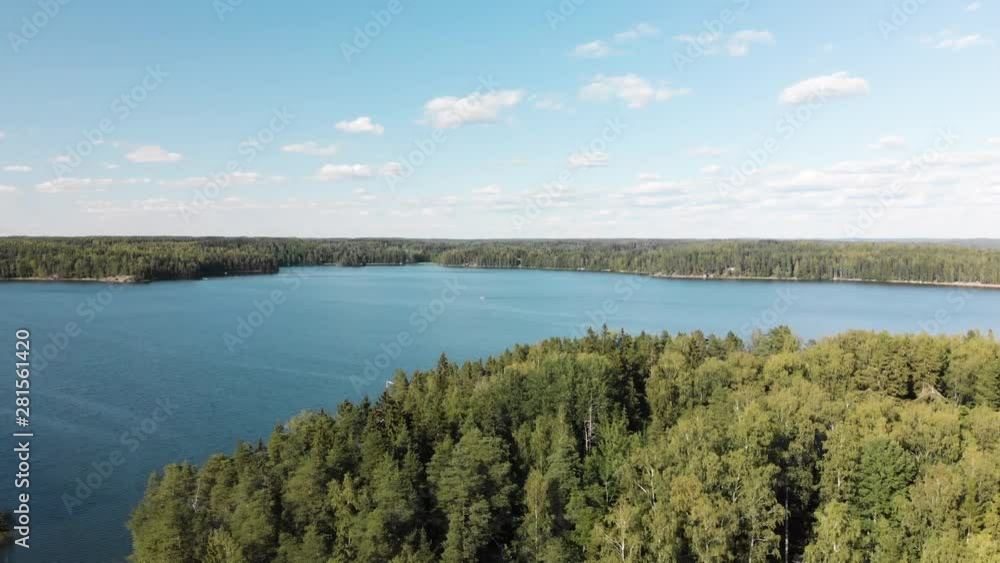Aerial, decreasing, drone shot of forest at the coast of Puujarvi lake, on a sunny, summer evening, in Karjalohja, Uusimaa, Finland Aerial, decreasing, drone shot of forest at the coast of Puujarvi lake, on a sunny, summer evening, in Karjalohja, Uusimaa, Finland