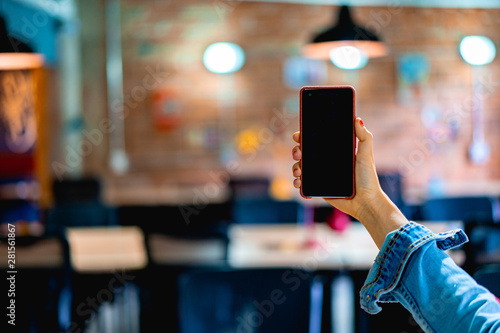 Girl holding a phone with a black screen with an office in the background
