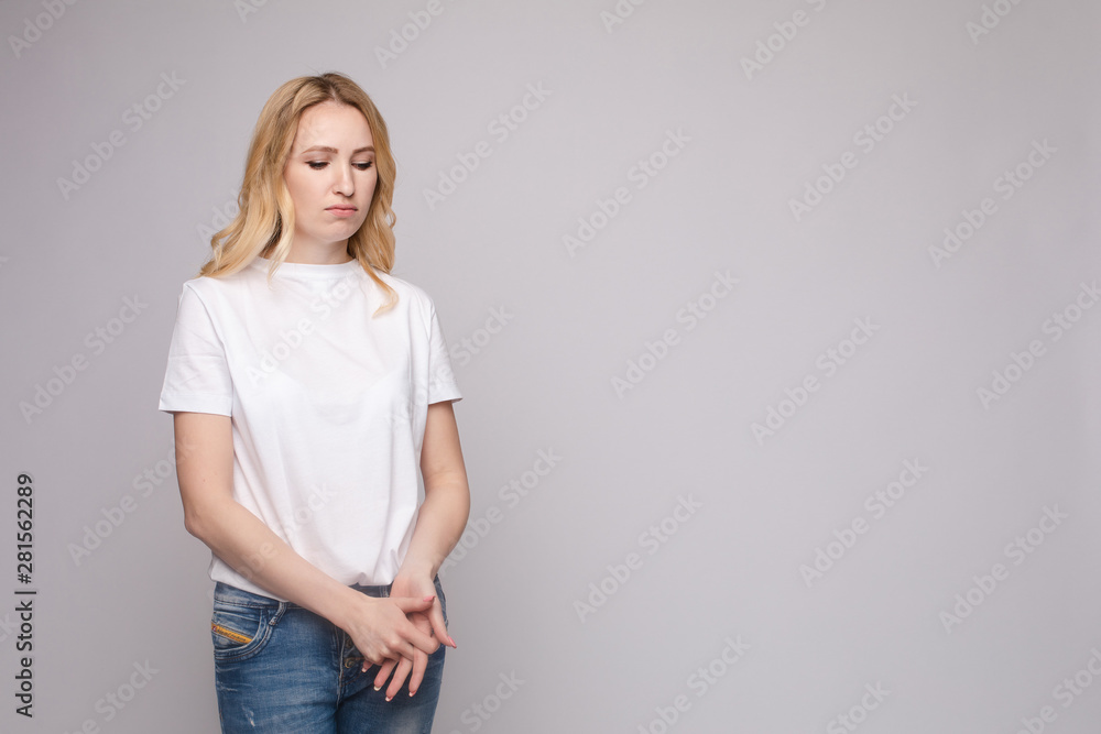 Upset young beautiful woman standing with crossed hands isolated at white studio background medium long shot. Unhappy European female looking down having negative emotion Upset young beautiful woman standing with crossed hands isolated at white studio background medium long shot. Unhappy European female looking down having negative emotion