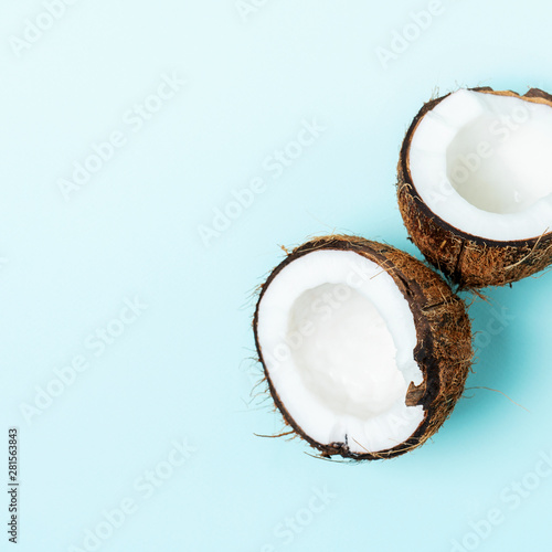 Halves of fresh coconut on a turquoise blue light background close-up.