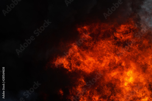 Dangerous strong red flames of industrial fire and dramatic black clouds of smoke covered sky. Atmospheric dispersion  selective and soft focus  motion blur from fire  high temperature from flames.