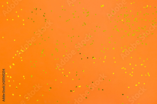 Orange halloween background with golden confetti. Festive surface.  Flat lay, top view.