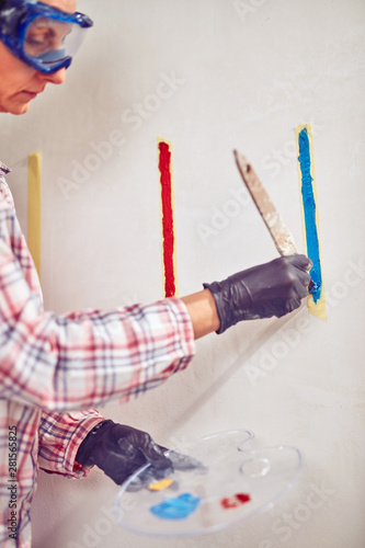 Working woman plastering / painting walls inside the house.