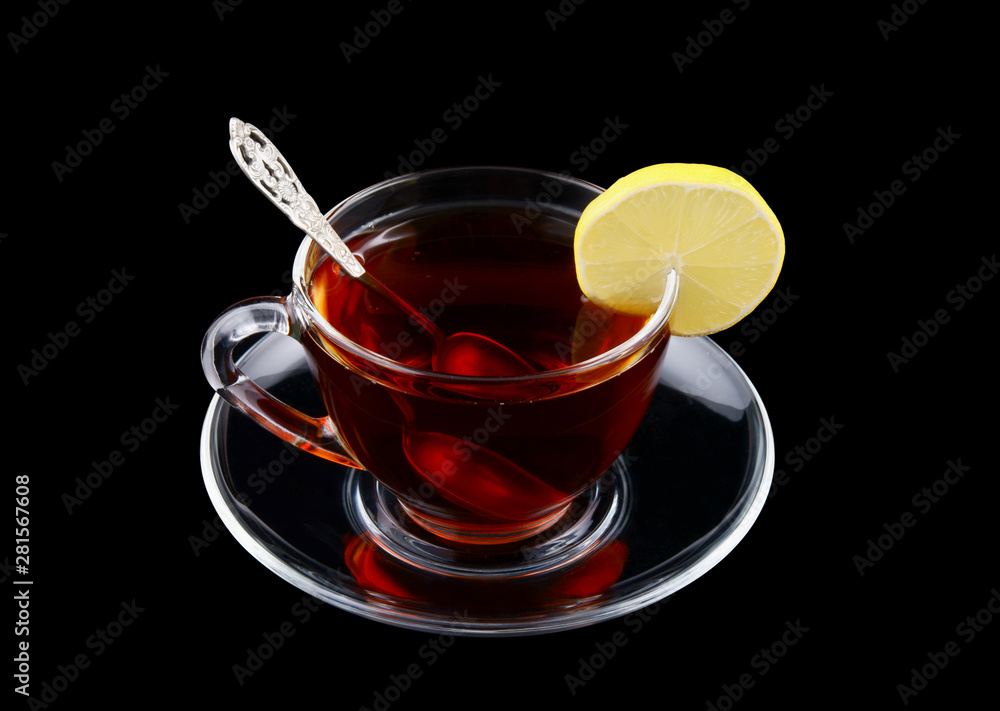 Transparent cup of tea with spoon and lemon isolated on black Transparent cup of tea with spoon and lemon isolated on black