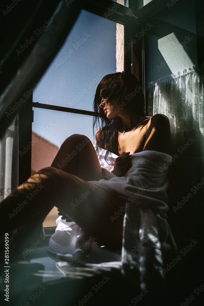 Sexy girl in a Bathrobe sitting on the windowsill