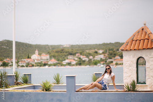 Fashion model in blue shorts and white shirt posing for photographer in beautiful inflow. Stylish woman in sunglasses