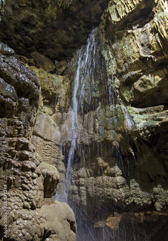 Geological rock formations and waterfall in an underground cave