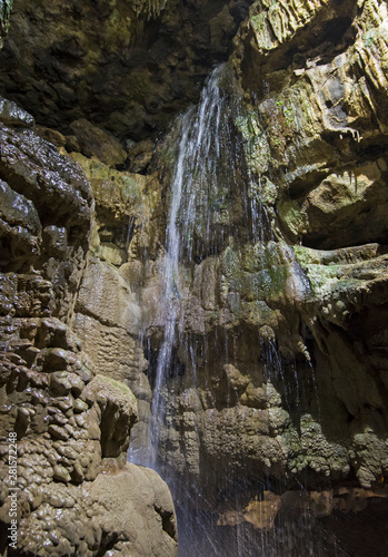 Geological rock formations and waterfall in an underground cave