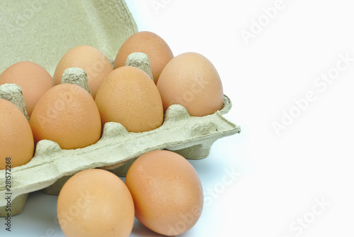 Isolated of nine chicken eggs in brown paper cardboard container on white background with copy space on the right.