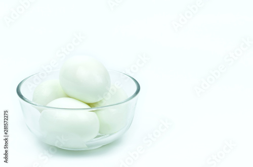 Isolated of four hard boiled chicken eggs in clear glass bowl on white background with copy space on the right.