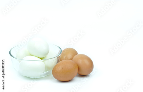 Isolated of four hard boiled chicken eggs in clear glass bowl and three raw eggs on white background with copy space on the right and upper.