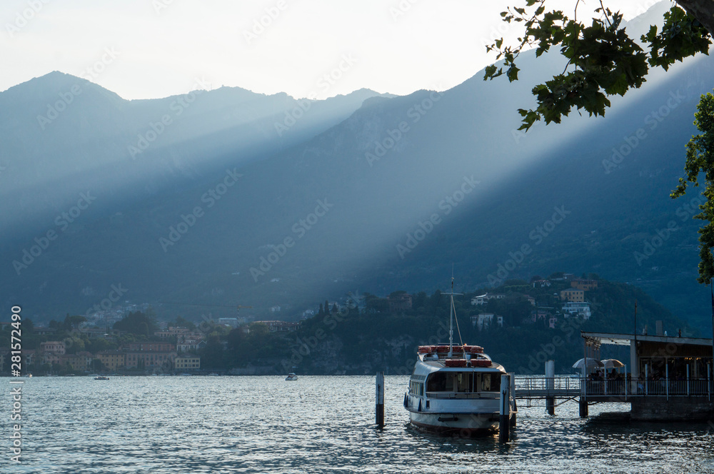 Lake Como in the Italian city of Lecco surrounded by mountains. A sailing yacht. Evening sunshine.