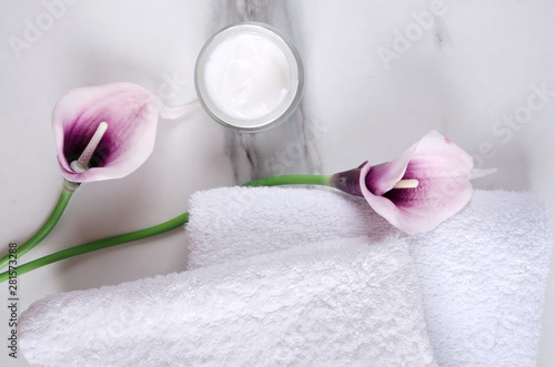 Purple callas  moisturizing cream  fresh white towels on the white surface