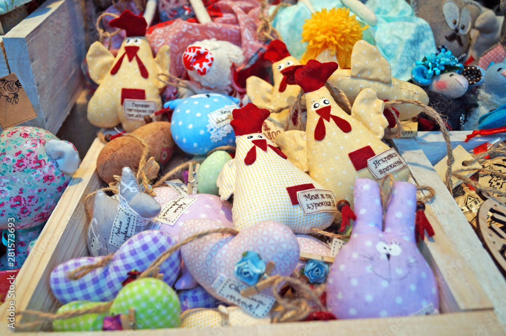 Fabric and ceramic toys of various shapes and colors are on the counter at the Christmas market.