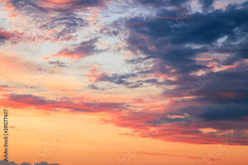 Heavenly summer background. Beautiful bright majestic dramatic evening sky at sunset or sunrise orange and blue with rays. The sun shines over the horizon against the backdrop of thunder clouds