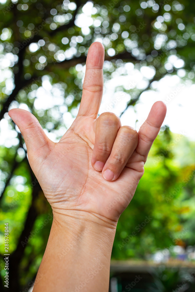 Woman's fore hand symbol meaning " i love you " in bokeh green garden