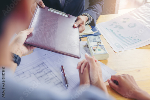 Husband and wife sign the loan agreement for home purchase to the bank officer.