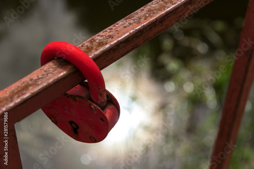 Close-up a red love lock hanging on a metal bridge railing