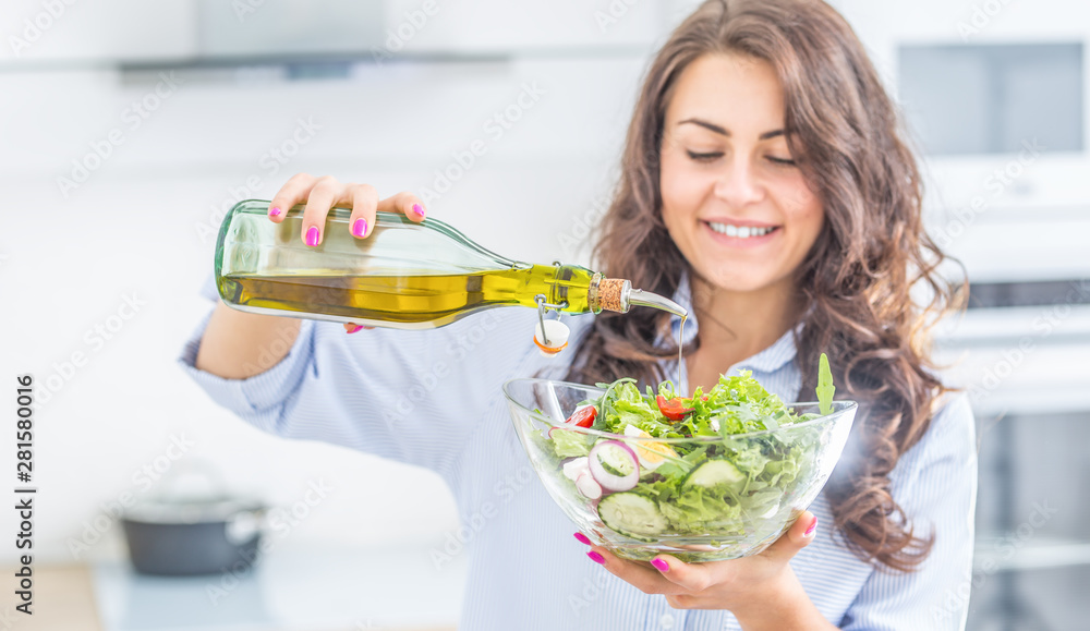 Young woman pouring olive oil in to the salad. Healthy lifestyle eating concept