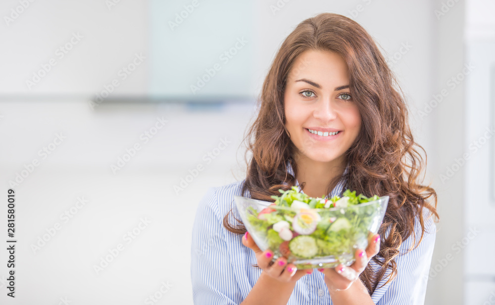 Young woman holding bowl with salad in her kitchen. Healthy lifestyle concept beautiful woman with mixed vegetable Young woman holding bowl with salad in her kitchen. Healthy lifestyle concept beautiful woman with mixed vegetable