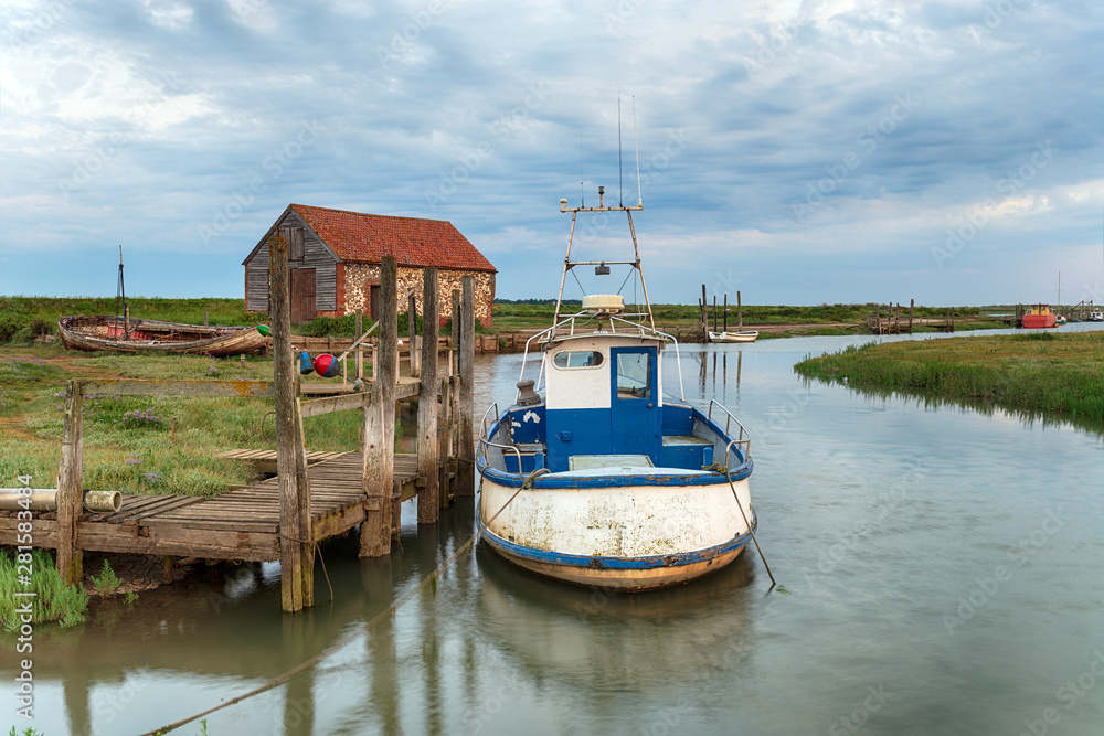 A fishing boat moored at a wodden jetty at Thornham