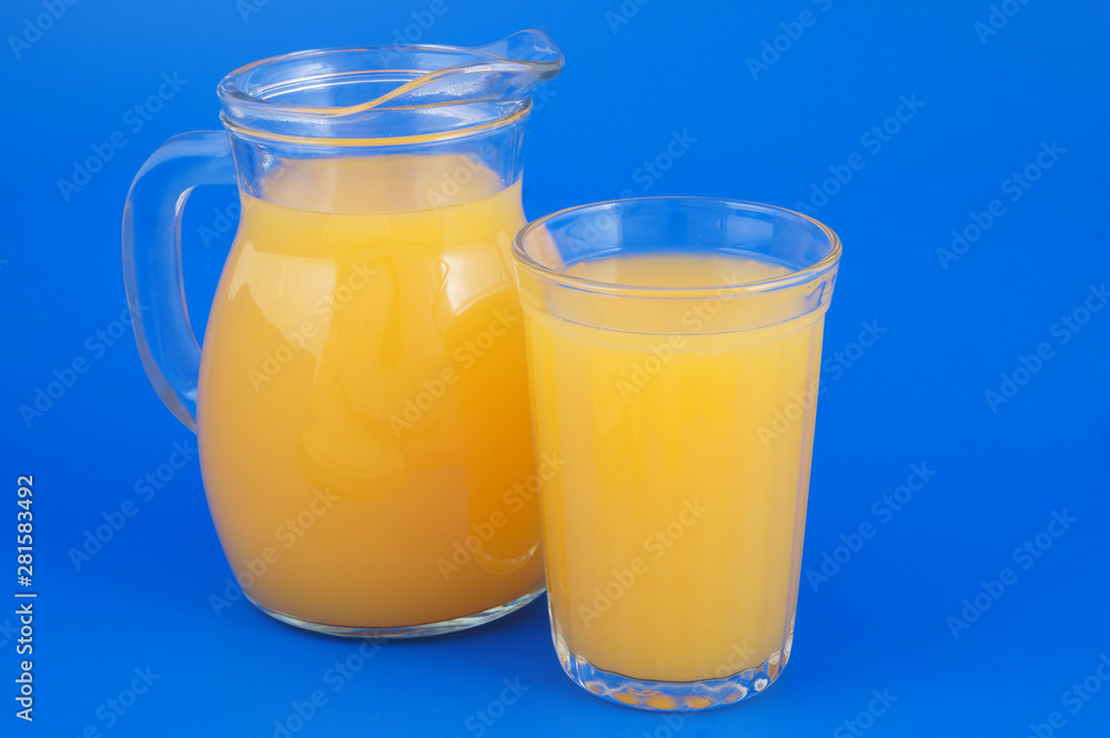 Orange juice in glass and pitcher on blue background Orange juice in glass and pitcher on blue background
