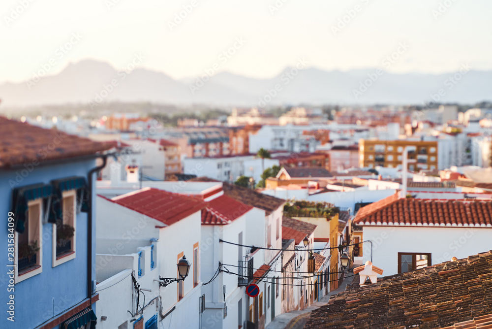 Old town of Denia view with houses with tile roofs and mountains at sunset.
