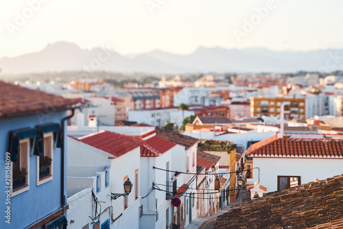 Old town of Denia view with houses with tile roofs and mountains at sunset. © bodiaphoto