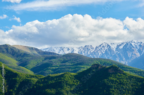 View of mountain snowy ridges on a bright sunny day with clouds in the sky.