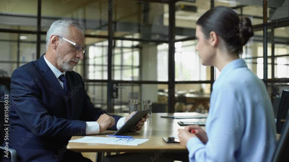 Aged businessman scrolling company app on tablet unhappy with work results Aged businessman scrolling company app on tablet unhappy with work results