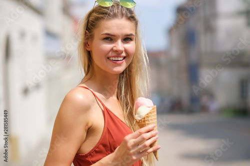 a sunny girl in a summer dress eats ice cream and walks around the streets of the town