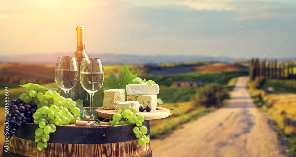 wine bottle and wine glass on wodden barrel. Beautiful Tuscany background