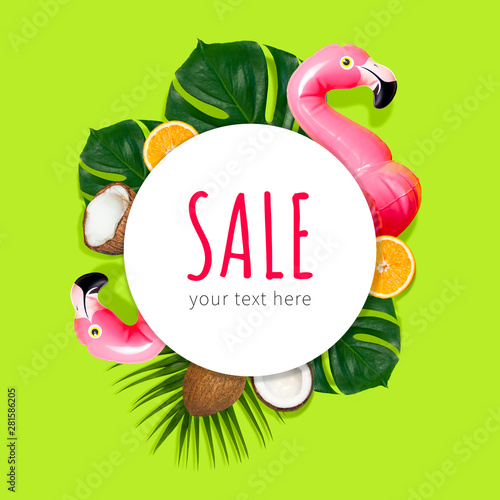 Creative concept of summer sales. Inflatable pink mini flamingo tropical palm leaf monstera coconut orange on green background pool float party. Flat lay Flamingo Trend Inflatable Toy. Discounts, sale