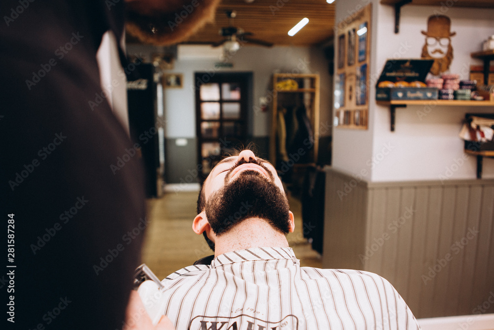 Work in the Barber shop. Barber shaving a bearded man in a barber shop, close-up. Master cuts hair and beard Work in the Barber shop. Barber shaving a bearded man in a barber shop, close-up. Master cuts hair and beard