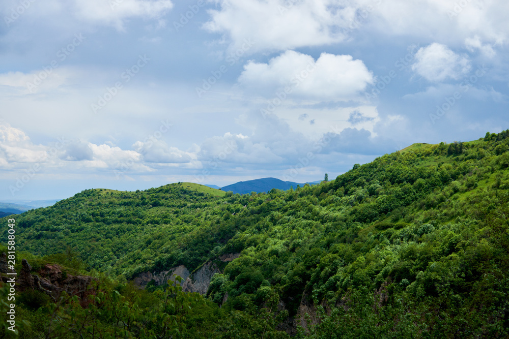 View of mountain snowy ridges on a bright sunny day with clouds in the sky.