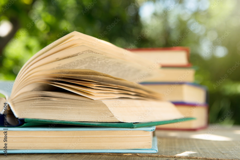 Open book on a wooden table in a garden. Sunny summer day, reading in a vacation concept Open book on a wooden table in a garden. Sunny summer day, reading in a vacation concept