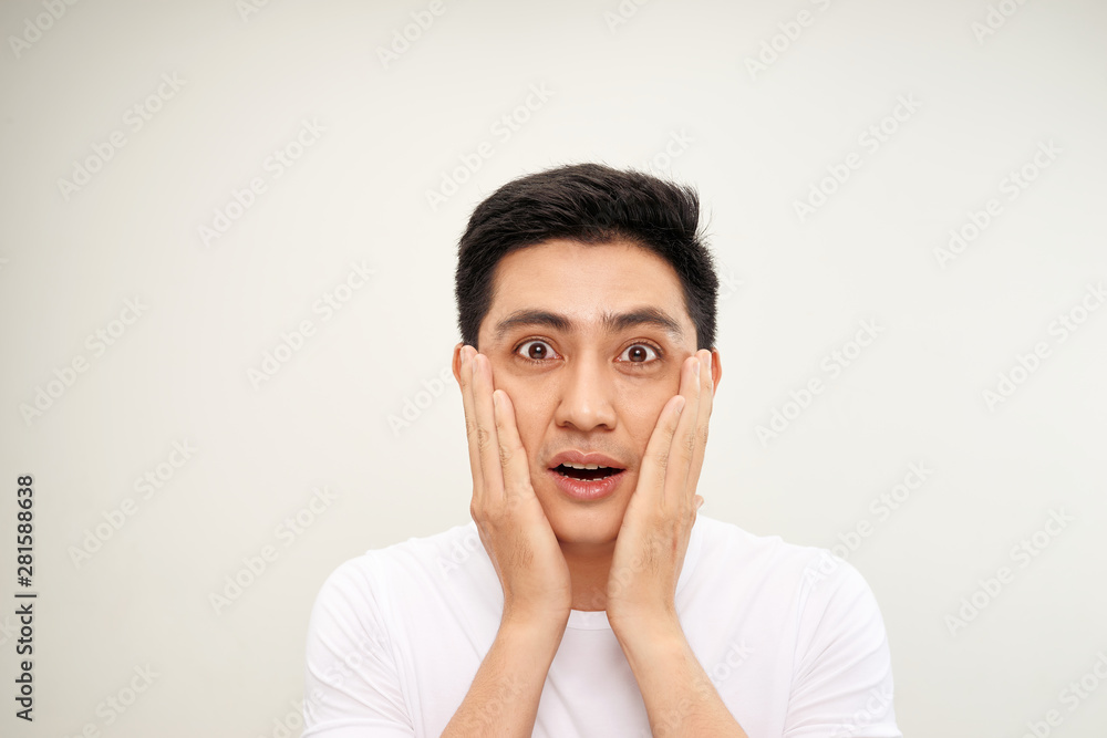Handsome Asian man is touching his face and smiling while looking into the mirror Handsome Asian man is touching his face and smiling while looking into the mirror