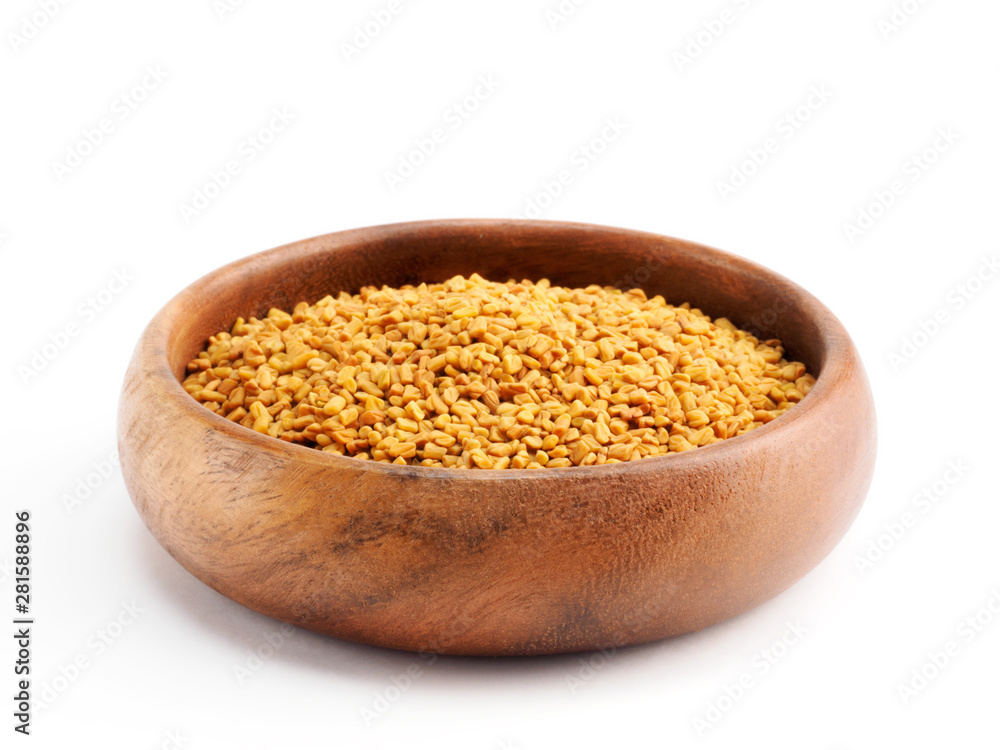 Fenugreek (Trigonella) in a wooden cup on a white background Fenugreek (Trigonella) in a wooden cup on a white background