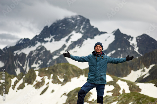 Hiker man stands against mountain top and smiles . Mountain trekking. Travel freedom concept. Copy space
