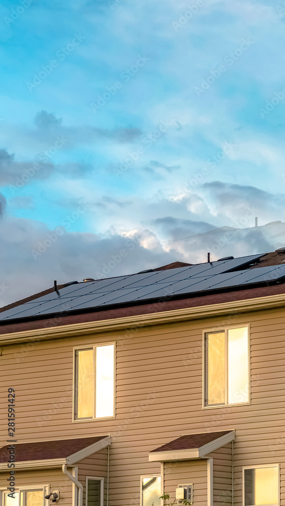 Vertical Multi storey home with solar panel on the roof against cloudy sky Vertical Multi storey home with solar panel on the roof against cloudy sky