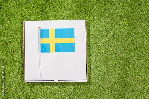 Paper box of pizza with Swedish Flag on the grass. Concept. Top view
