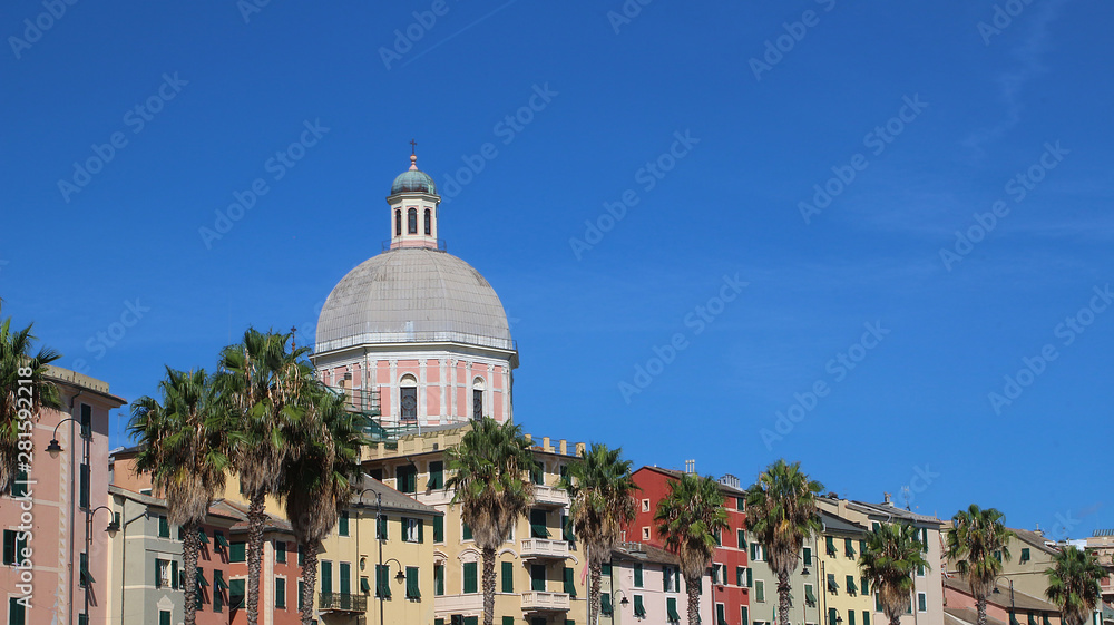 Colorful buildings at the seafront road and the tower of the Catholic church in Genoa Pegli, Italy